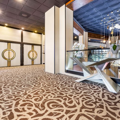 A modern interior with patterned carpet, decorative wall mirrors, and elegant furniture seen near a room entrance with circular designs.