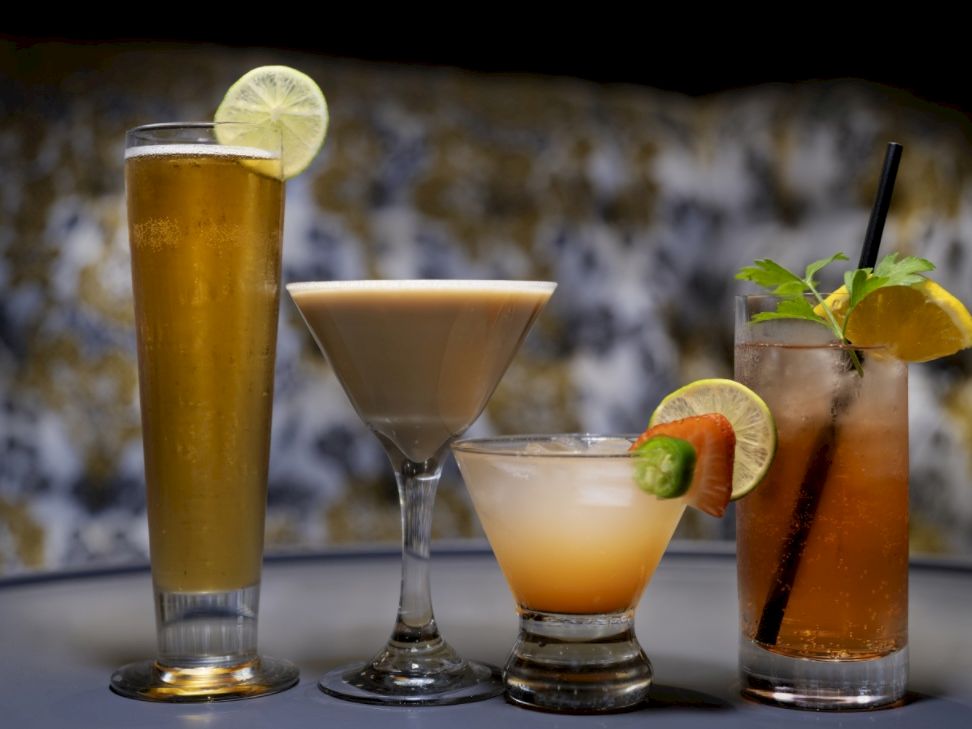 Four cocktails with citrus and mint garnishes on a bar table, ready to sip.