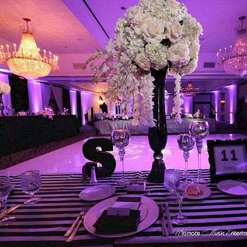 The image shows a decorated event table with flowers, tableware, and numbers in a dimly lit room with chandeliers and purple lighting.