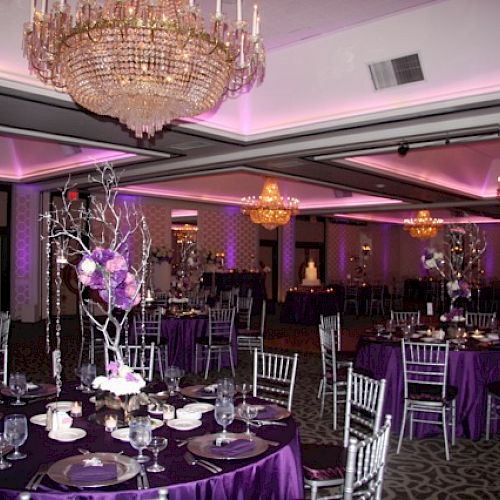 The image shows an elegantly decorated banquet hall with purple lighting, chandeliers, and tables set with purple tablecloths and floral centerpieces.