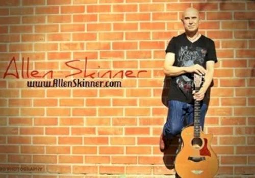 This image shows a person standing against a brick wall holding an acoustic guitar, with the text 